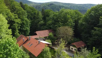 Panoramablick auf das Anwesen, eingebettet in ein Tal mit bewaldeten Hügeln und grüner Landschaft.