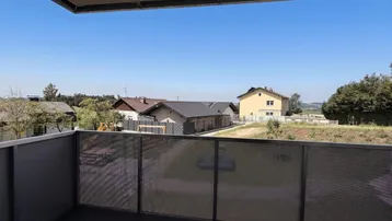 Moderner Balkon mit Fliesenboden und weitem Blick über die Wohngegend und grüne Landschaft.