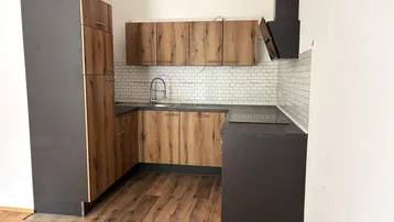 Moderne Küche mit Holzfronten, dunklen Arbeitsplatten und weißem Fliesenspiegel.