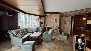 Gemütliches Wohnzimmer mit Kamin, Fliesenboden und bequemen Ledersofas.