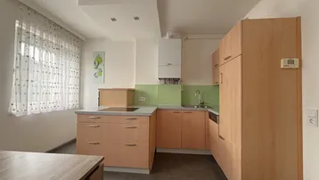 Helle Küche mit Holzschränken, grüner Rückwand, Induktionskochfeld und Essbereich.
