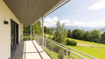 Geräumiger Balkon mit moderner Metallbrüstung und weitem Blick über die grüne Landschaft und Berge.
