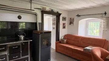 Gemütliches Wohnzimmer mit Kaminofen, Holzbalkendecke und bequemer Couch.
