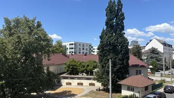 Blick auf einen Spielplatz und umliegende Gebäude unter blauem Himmel.