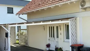 Vorderansicht des Hauses mit überdachtem Eingangsbereich und Carport.