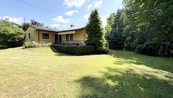 Großzügiger Gartenbereich mit Rasenfläche und einem charmanten gelben Einfamilienhaus im Hintergrund.