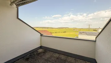 Geräumiger Balkon mit weitem Blick über grüne Felder und ländliche Umgebung.
