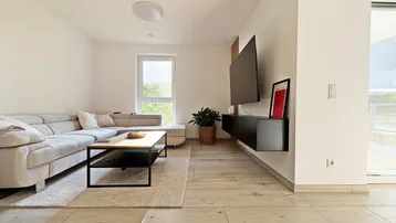 Helles Wohnzimmer mit modernem Sofa, Couchtisch und Wandfernseher, ausgestattet mit Holzoptikfliesen.