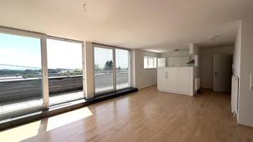 Heller, offener Wohn-Essbereich mit großen Fenstern, Holzboden und Zugang zur Terrasse.