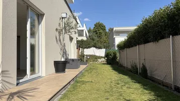 Langer, schmaler Gartenbereich entlang des Hauses mit hoher Hecke und gepflegtem Rasen.