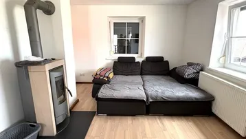 Helles Wohnzimmer mit bequemer Schlafcouch und einem modernen Holzofen für gemütliche Abende.