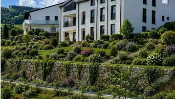Modernes Gebäude mit Photovoltaikanlage und einem aufwendig gestalteten, terrassierten Gartenbereich.