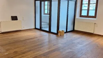 Heller Raum mit Holzboden und einer modernen Glasabtrennung in der Mitte.