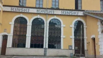 Gelbe Fassade eines historischen Gebäudes mit großen Bogenfenstern und dem Schriftzug "KINSKI" über dem Eingangsbereich.
