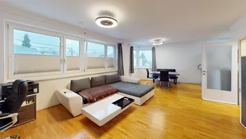 Heller offener Wohn- und Essbereich mit Parkettboden, bequemer Couch und großzügigen Fenstern.