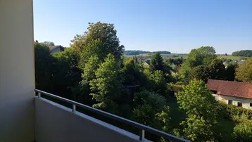 Balkon mit weitem Blick ins Grüne und über die ländliche Umgebung an einem sonnigen Tag.