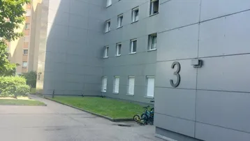 Moderne Fassade eines Mehrfamilienhauses mit vielen Fenstern und der Hausnummer 3.