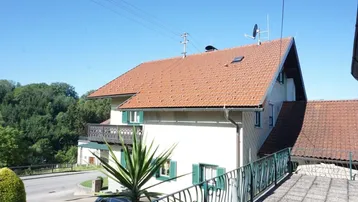 Blick auf das Haus mit Satteldach und einem Balkon mit schmiedeeisernem Geländer.