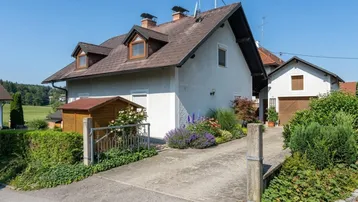 Ansicht des Hauses von der Auffahrt mit gepflegtem Vorgarten und ländlicher Umgebung.