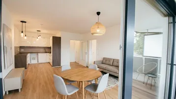 Heller offener Wohn-Essbereich mit integrierter Küche, Parkettboden und Zugang zum Balkon.