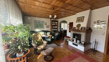 Gemütliches Wohnzimmer mit Holzkassettendecke, Kamin und traditioneller Einrichtung.