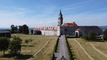 Beeindruckendes historisches Schloss mit weitläufiger Zufahrt und gepflegter Grünanlage.
