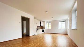 Moderne Einbauküche in offenem Wohnbereich mit hellem Parkettboden und viel Tageslicht.