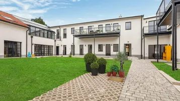 Gepflegter Innenhof mit Rasenfläche, Gehwegen und modernen Gebäuden mit Balkonen.