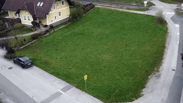 Luftaufnahme eines Hauses mit großem Rasengrundstück, angrenzender Straße und Bahnübergang.
