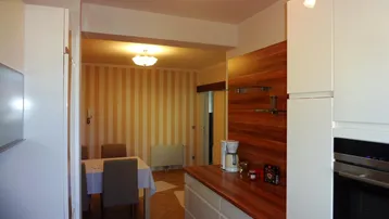 Moderne Küche mit weißen Schränken, Holztheke und Blick in den Essbereich.