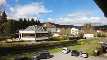 Weitläufige Umgebung mit Wohngebäuden, Grünflächen und Parkplätzen unter blauem Himmel.