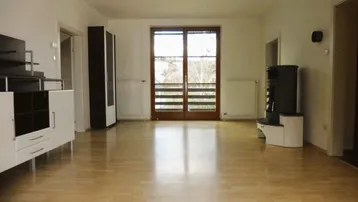 Helles Wohnzimmer mit Parkettboden, Kaminofen und Zugang zum Balkon.