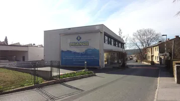 Außenansicht eines Geschäftsgebäudes mit großer Werbetafel an der Fassade und angrenzender Straße.