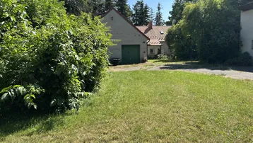 Das Anwesen zeigt ein Haus mit Garage und weitläufiger Rasenfläche, umgeben von Bäumen.