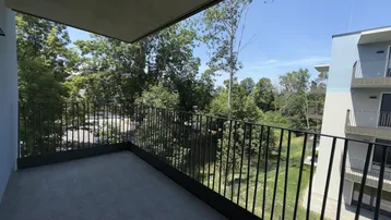 Geräumiger Balkon mit Blick ins Grüne und auf die umliegenden modernen Gebäude.