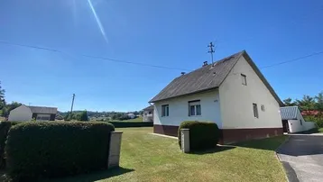 Hausfassade mit gepflegtem Vorgarten und weitem Blick in die Landschaft.