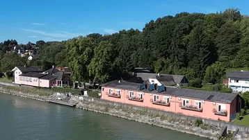 Luftaufnahme der Gebäude am Seeufer, umgeben von grünen Wäldern und Hügeln.