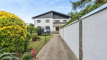 Großzügiger Gartenbereich mit Rasenfläche, Hecken und Trampolin hinter dem modernen Wohnhaus.
