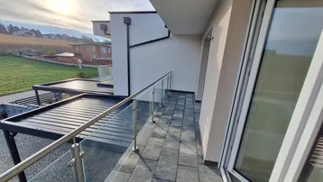 Geräumiger Balkon mit modernem Glasgeländer und Blick auf die Umgebung.
