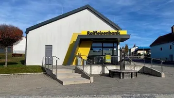 Moderne Bankfiliale mit markanter gelber Fassade und barrierefreiem Zugang über eine Rampe.