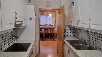 Helle Küche mit weißen Schränken, Fliesenrückwand und Blick in den Essbereich.