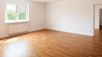 Helles, leeres Zimmer mit Parkettboden und Fenster mit Blick ins Grüne, bereit zur Einrichtung.