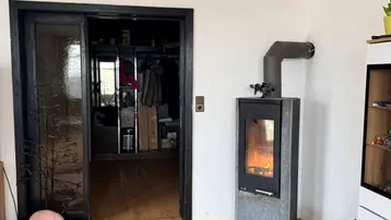 Wohnzimmer mit Laminatboden und einem modernen Holzofen, der Wärme spendet.
