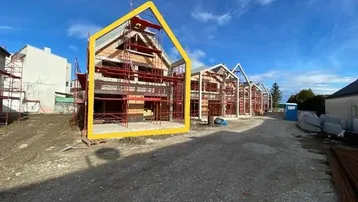 Reihenhäuser im Bau mit Gerüsten unter blauem Himmel, bereit für den Innenausbau.