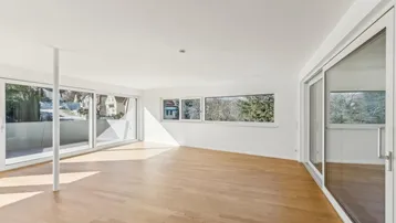 Lichtdurchfluteter Wohnbereich mit Parkettboden und Zugang zu mehreren Balkonen oder Terrassen.