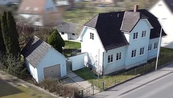 Luftaufnahme des hellblauen Hauses mit angrenzender Garage und gepflegtem Gartenbereich.