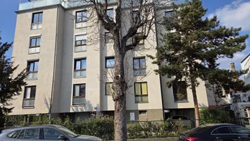 Modernes Mehrfamilienhaus mit mehreren Etagen und Flachdach in städtischer Umgebung.