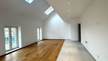 Geräumiger, heller Raum mit Dachschrägen, Oberlichtern und einer Kombination aus Holz- und Fliesenboden.