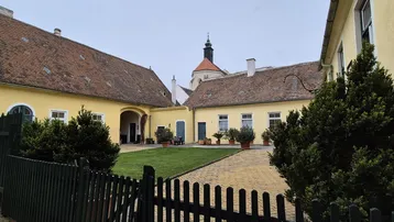 Historischer Innenhof mit gepflegtem Rasen, gepflastertem Weg und alten Gebäuden.