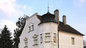 Historisches Eckgebäude mit markanter Architektur und hellgrauer Fassade an einer Straße gelegen.
